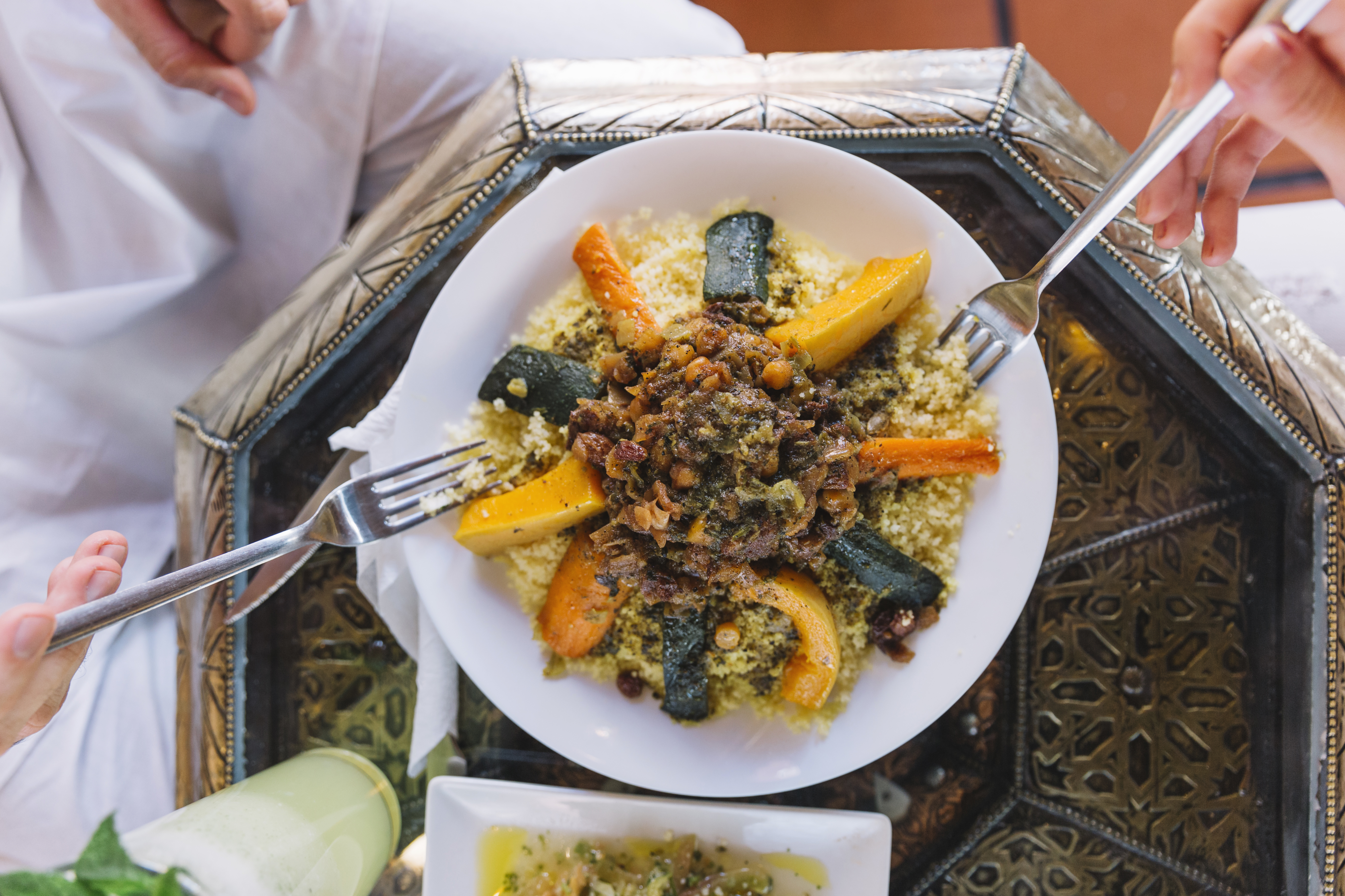 Plat traditionnel algérien servi avec légumes, semoule et sauce, style photographie culinaire